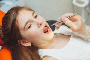Young patient receiving dental examination with mirror tool in Ruidoso dental office.