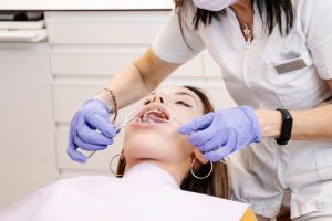 Dentist examining patient's teeth and gums during preventive dental care visit.