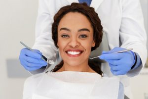Smiling patient with dentist holding dental tools during oral examination at Ruidoso dental practice.