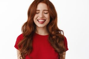 Woman with red hair smiling brightly, displaying a healthy white smile.