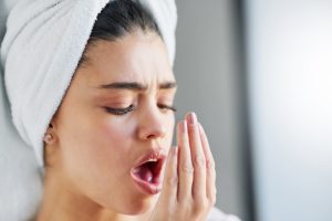 Woman with dry mouth symptoms touching her face in discomfort, illustrating bad breath concerns.